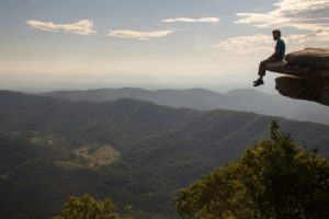 Hiker sitting on a ledge overlooking a valley