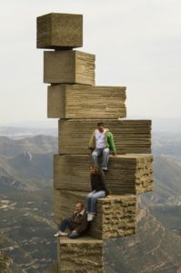 Sculpture of blocks balancing precariously with people on them