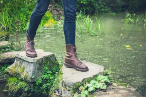 Woman stepping on stones across water