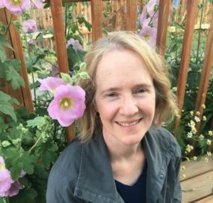 Terry Kerler, LPC sitting in garden with pink flowers